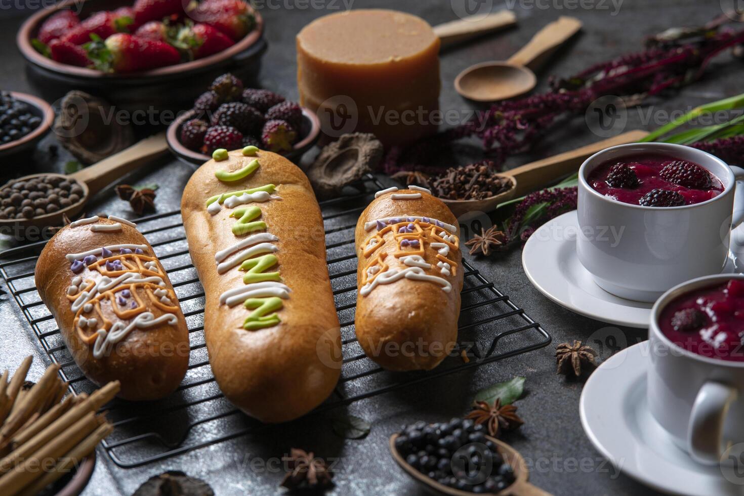 Guaguas de Pan with cups of Colada Morada, traditional Ecuadorian food for the day of the dead, surrounded by the ingredients to cook the colada photo