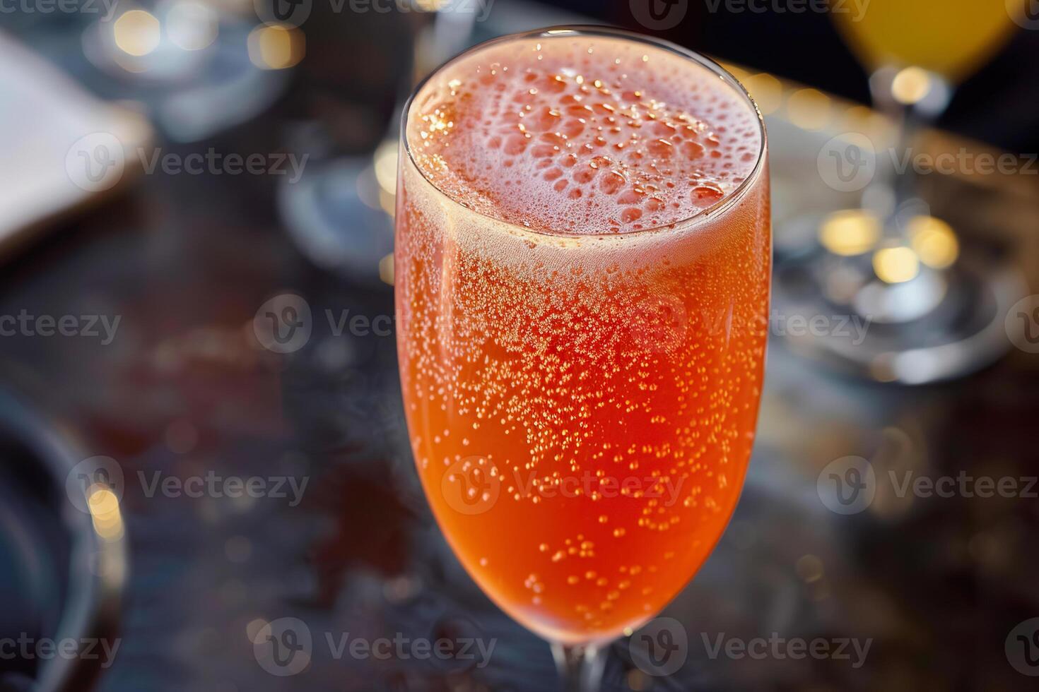 A closeup of a vibrant Bellini cocktail in a tall glass, highlighting its bubbles photo