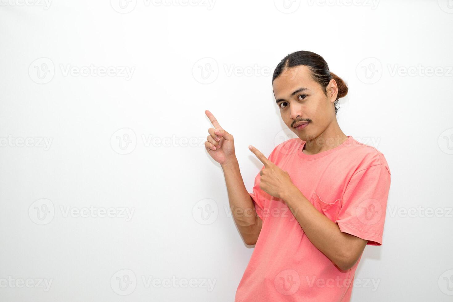 Asian, Indonesian man standing wearing pink shirt pointing right, left, up, down and presenting using hand gestures. Isolated on white background photo