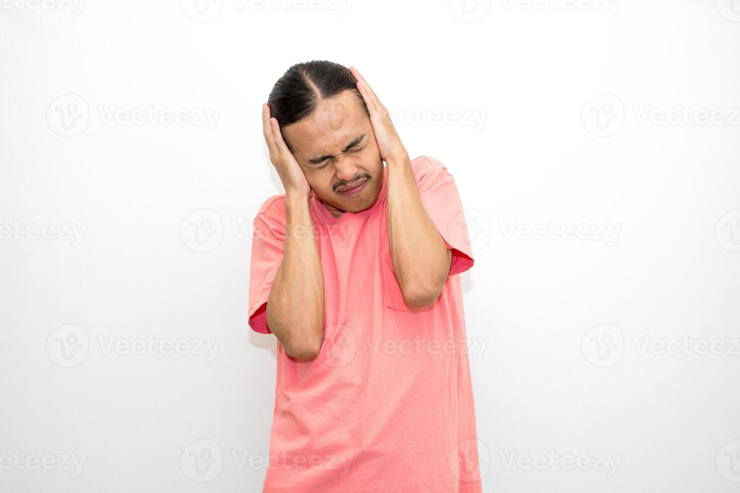 An Indonesian, Asian man wearing a pink tshirt having a headache, chest pain and stomach ache with hands holding head, chest and stomach. isolated in white background photo