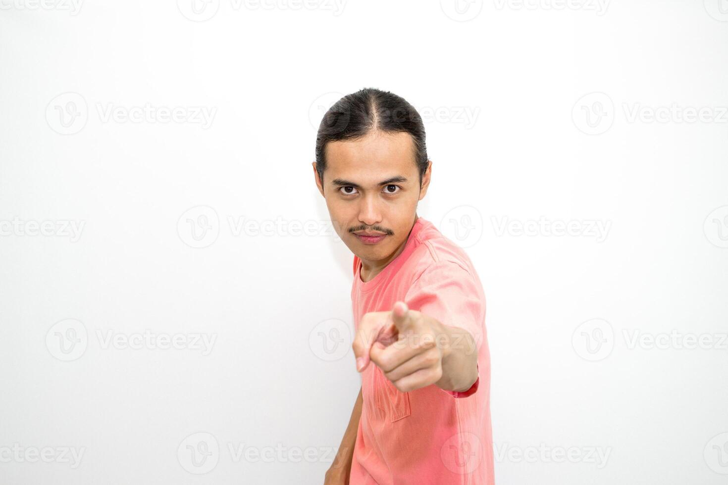 An Indonesian, Asian man wearing a pink tshirt shows a fierce expression as if he is angry or frustrated. isolated in white background photo