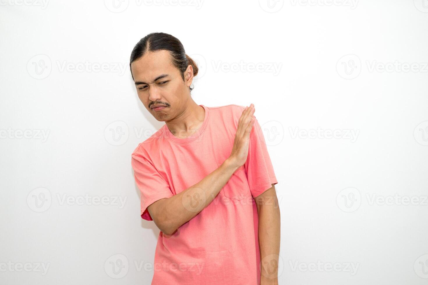 An Indonesian, Asian man wearing a pink tshirt shows a fierce expression as if he is angry or frustrated. isolated in white background photo