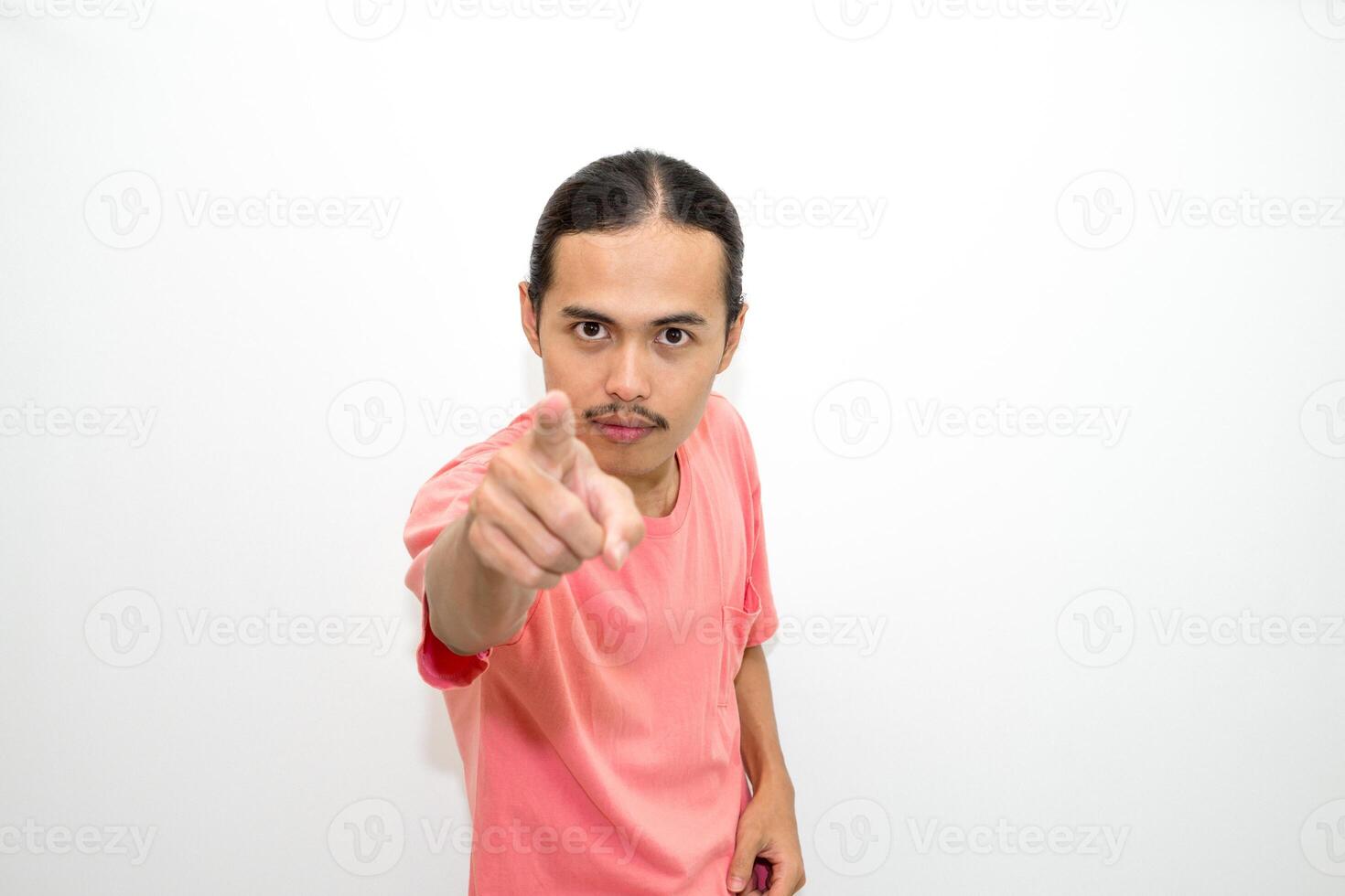 An Indonesian, Asian man wearing a pink tshirt shows a fierce expression as if he is angry or frustrated. isolated in white background photo