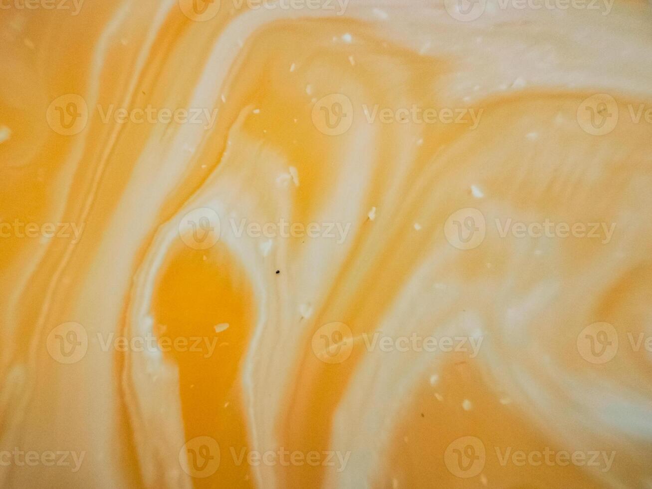 High-angle full-frame shot of coffee and milk swirling together, featuring frothy foam bubbles and creating a captivating abstract pattern. photo