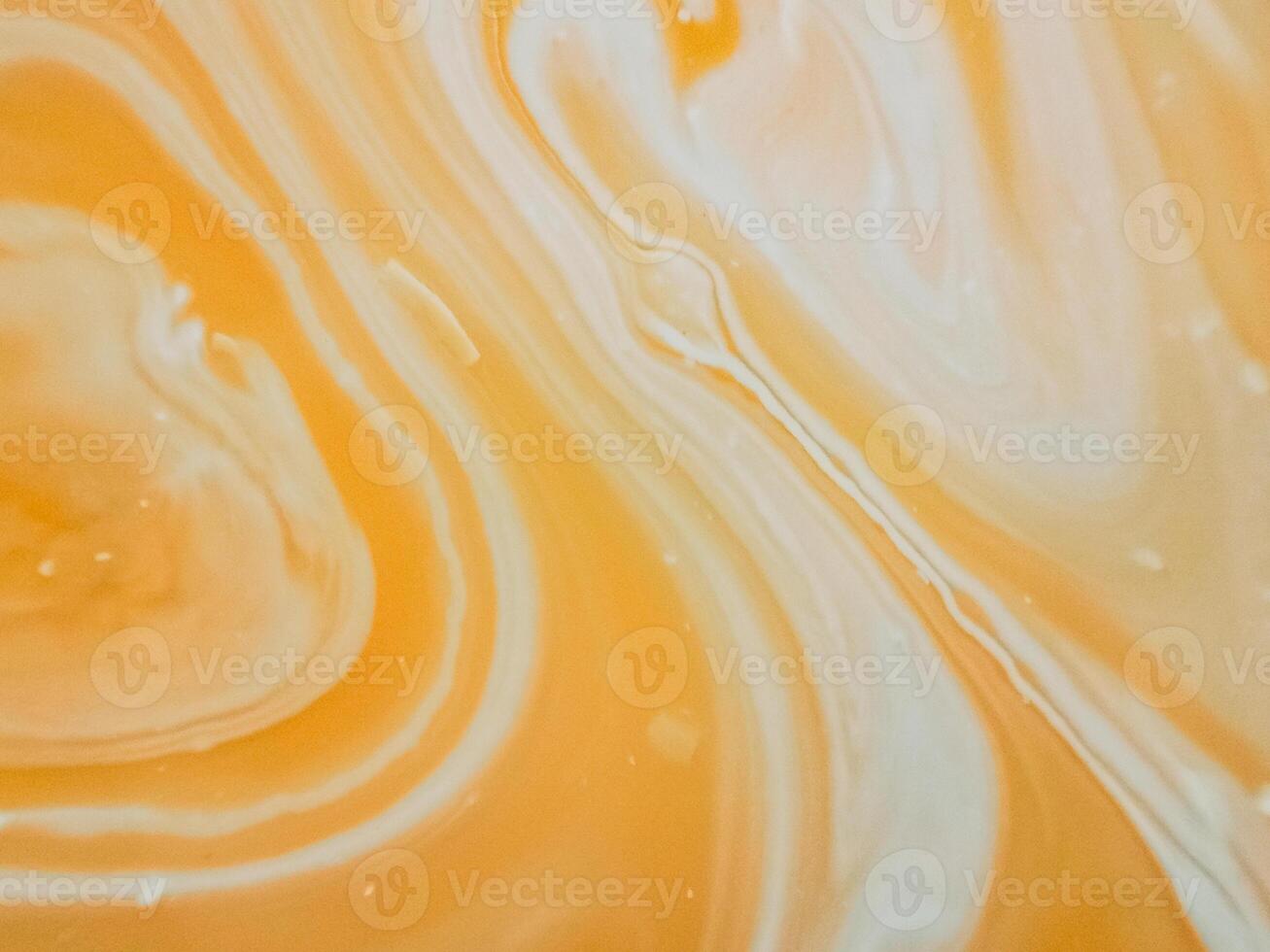 High-angle full-frame shot of coffee and milk swirling together, featuring frothy foam bubbles and creating a captivating abstract pattern. photo