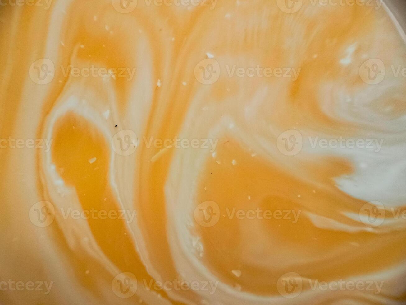 High-angle full-frame shot of coffee and milk swirling together, featuring frothy foam bubbles and creating a captivating abstract pattern. photo