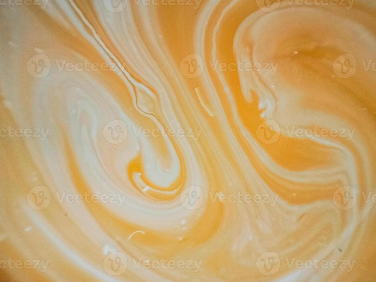 High-angle full-frame shot of coffee and milk swirling together, featuring frothy foam bubbles and creating a captivating abstract pattern. photo