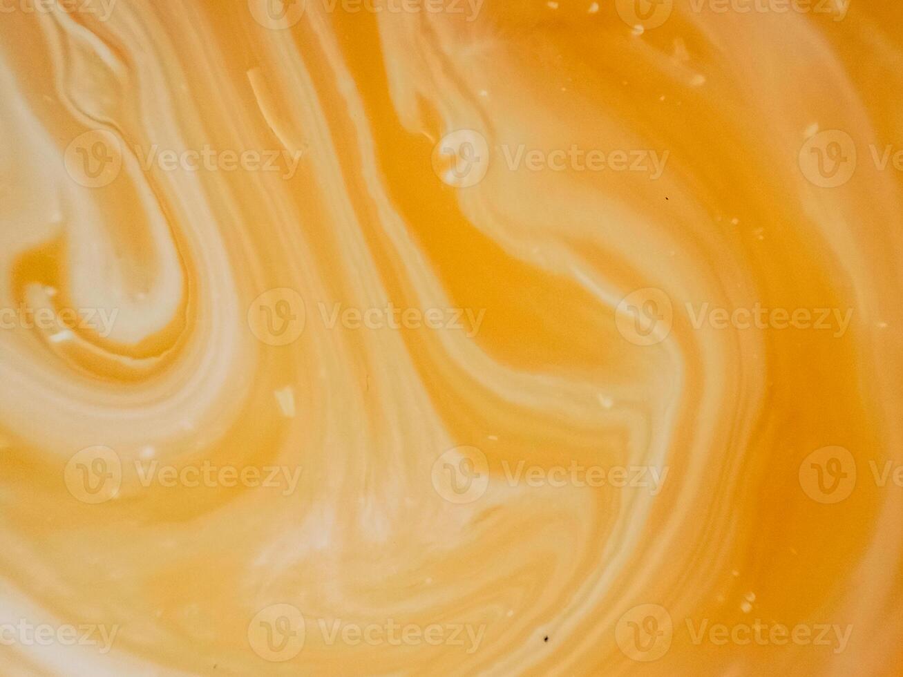 High-angle full-frame shot of coffee and milk swirling together, featuring frothy foam bubbles and creating a captivating abstract pattern. photo