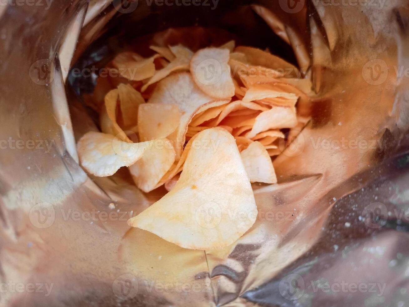 Open package with fresh casava chips. Top view, flat lay photo