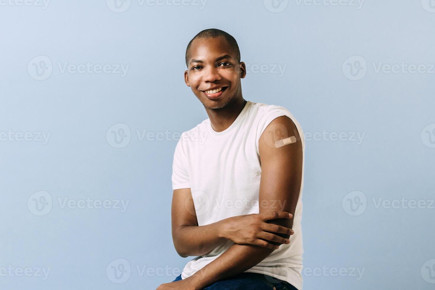 portrait of a young African American man with bandage on his arm. black man showing his arm with a bandage for the coronavirus vaccine. photo