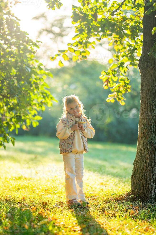 Little girl having fun with tree leaves in the autumn park in Prague, Europe. High quality photo