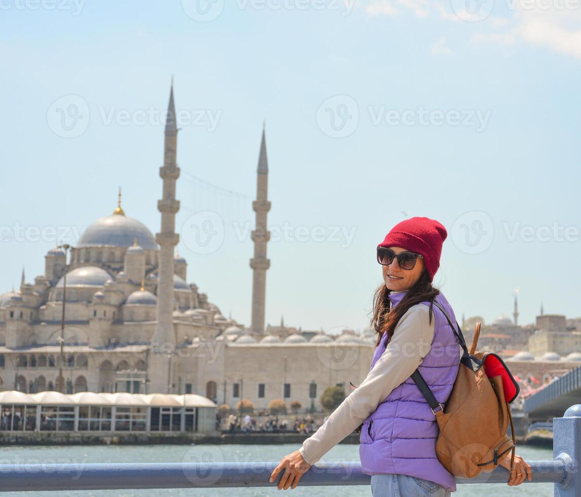 A young traveler with a backpack on her back looks at the camera in front of a mosque in Istanbul. photo