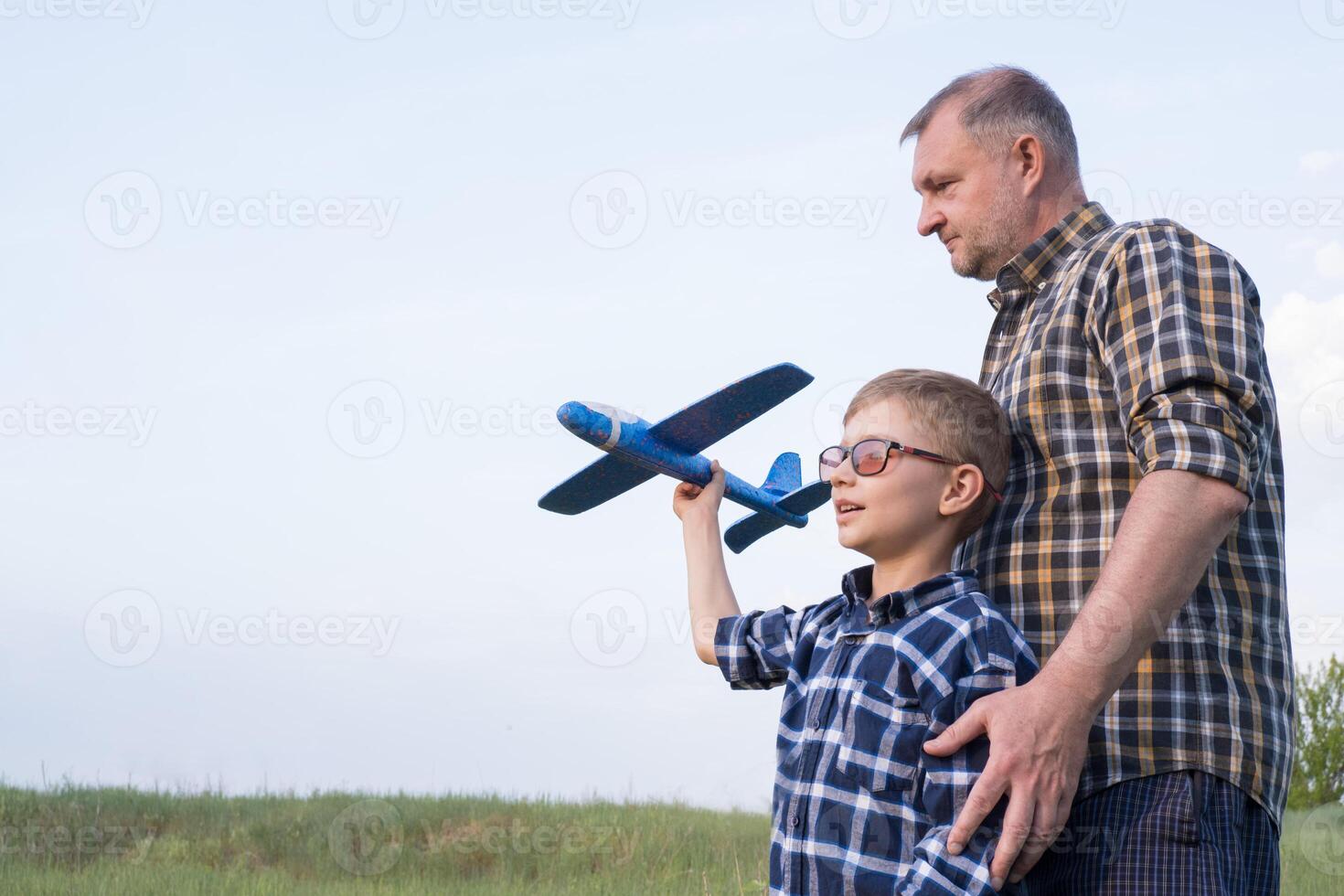 Father and son having fun in the field playing with an airplane photo