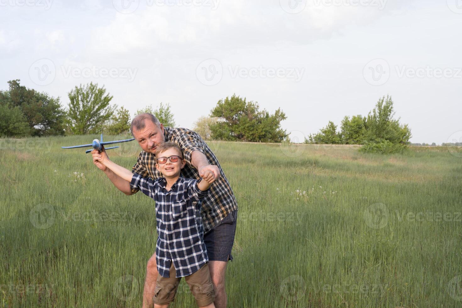 Father and son having fun in the field playing with an airplane. Father's day concept. photo