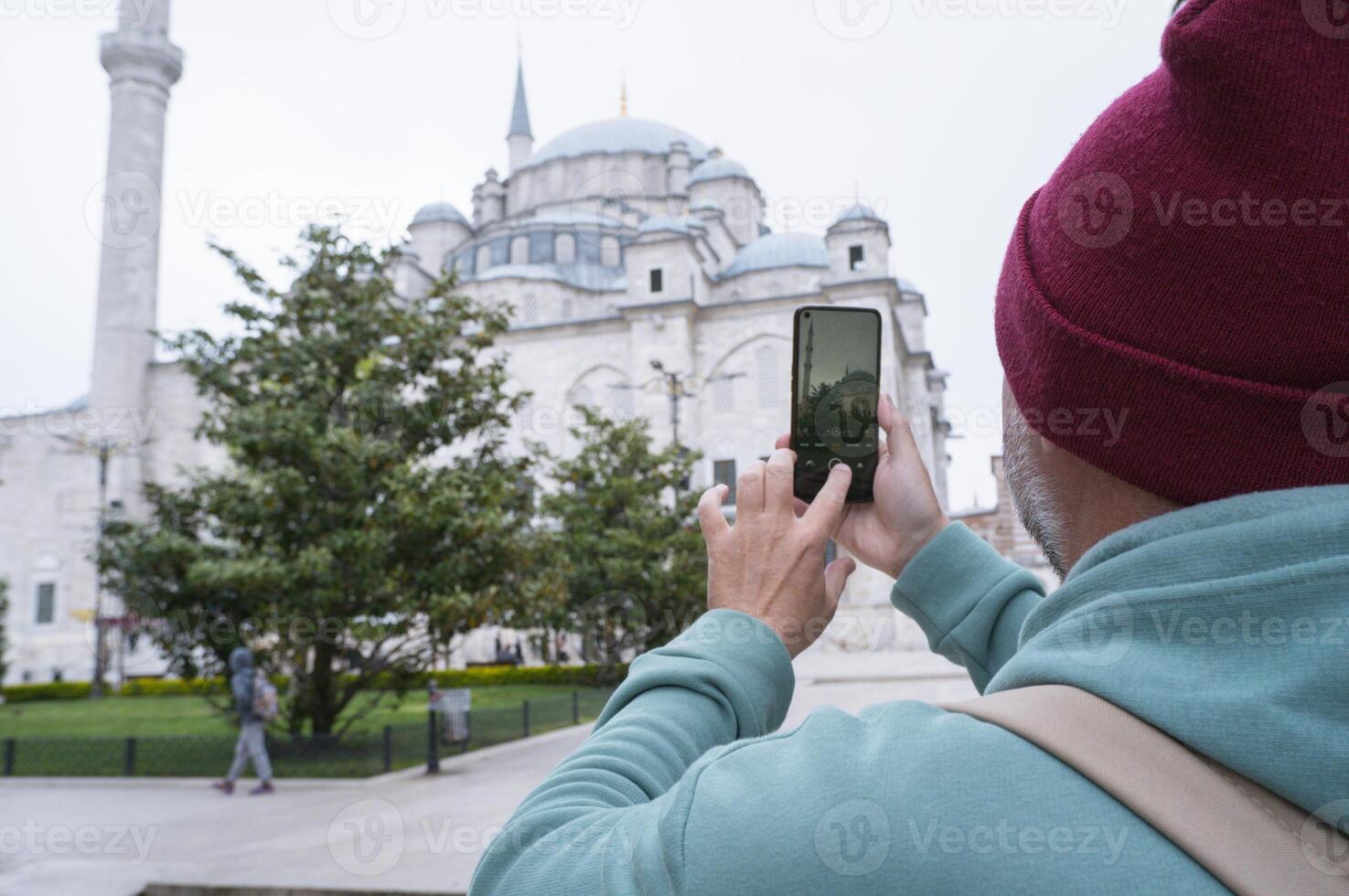 A male tourist takes a photo of the Fatih Mosque in Istanbul, Turkey as a keepsake.