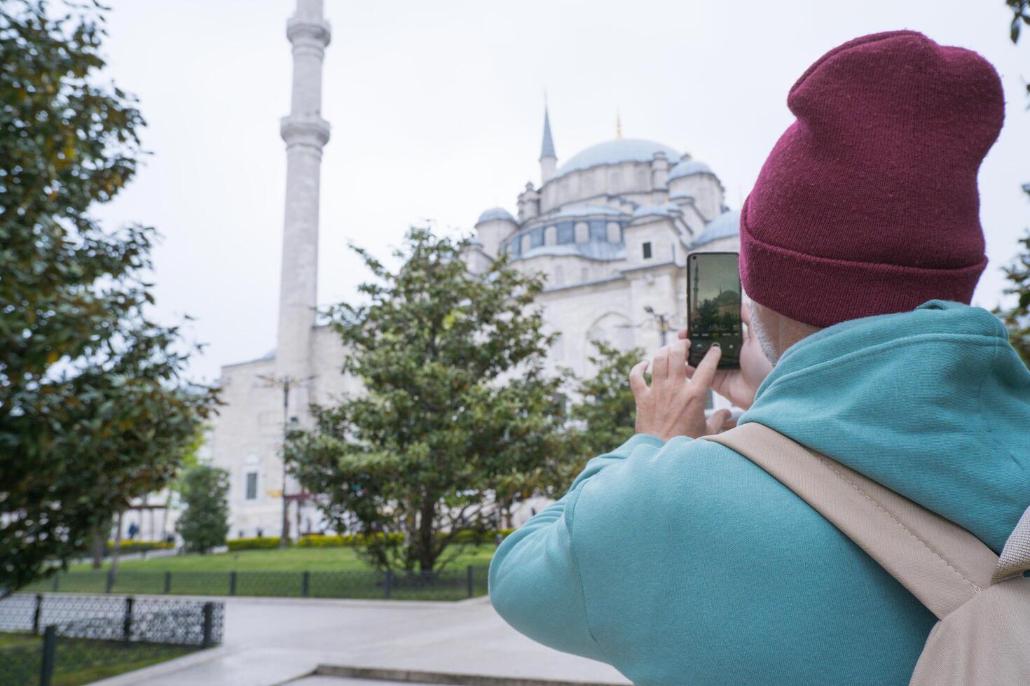 A male tourist takes a photo of the Fatih Mosque in Istanbul, Turkey as a keepsake.