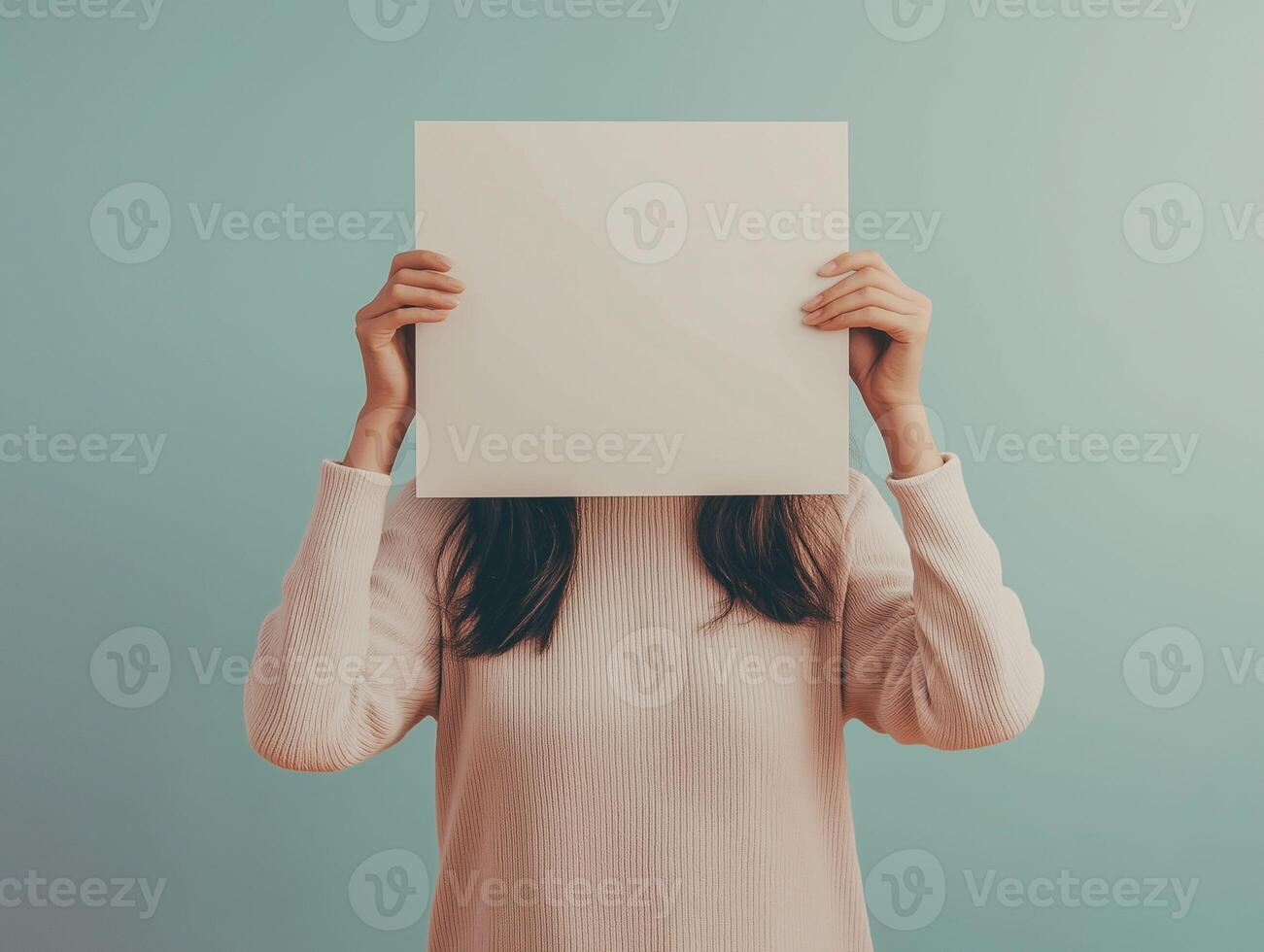 Woman holding up a blank paper over her face photo