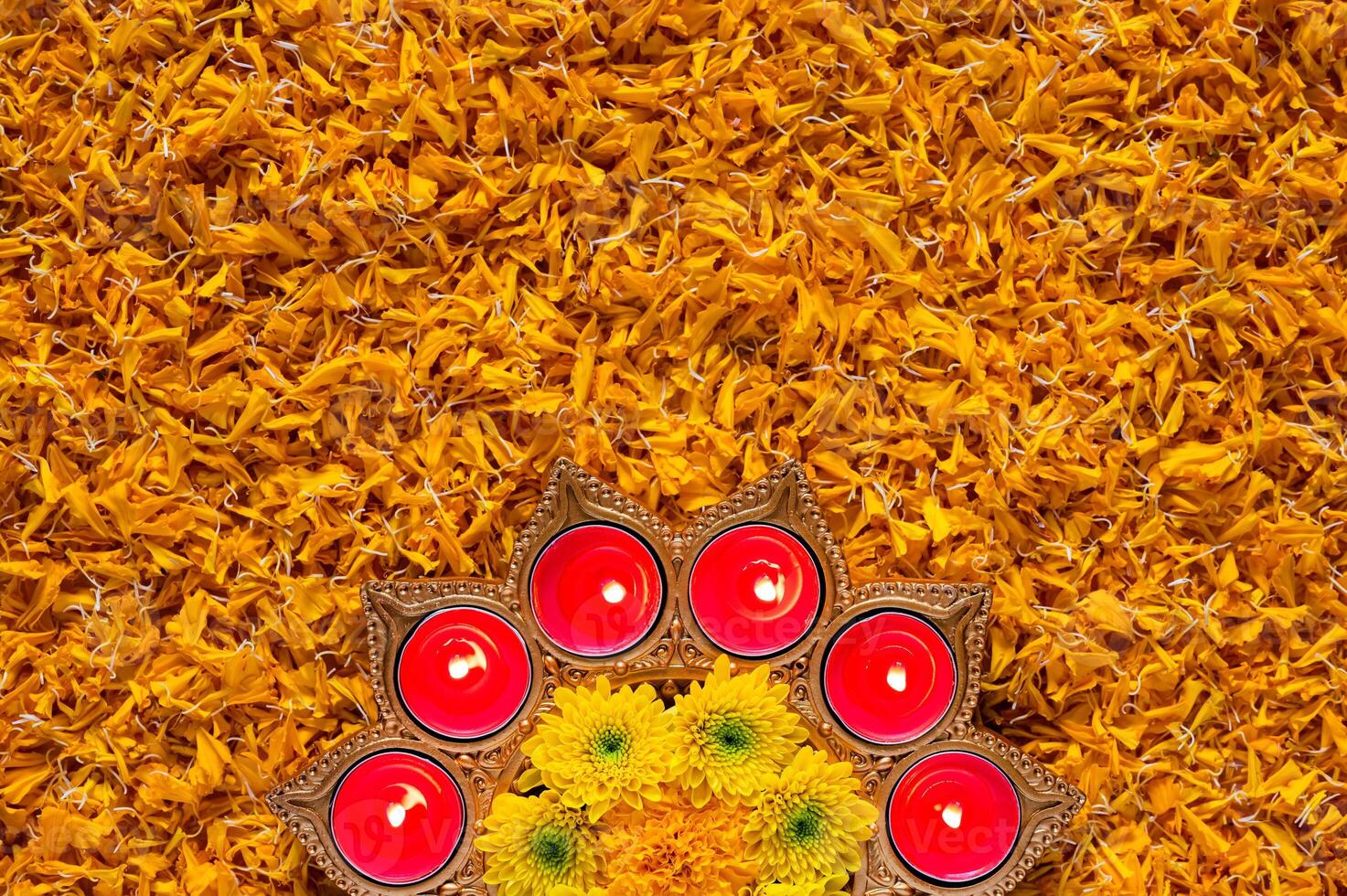 Decorative diya lamp lit with blurred focus flame for Diwali festival puts on orange marigold petals background. photo