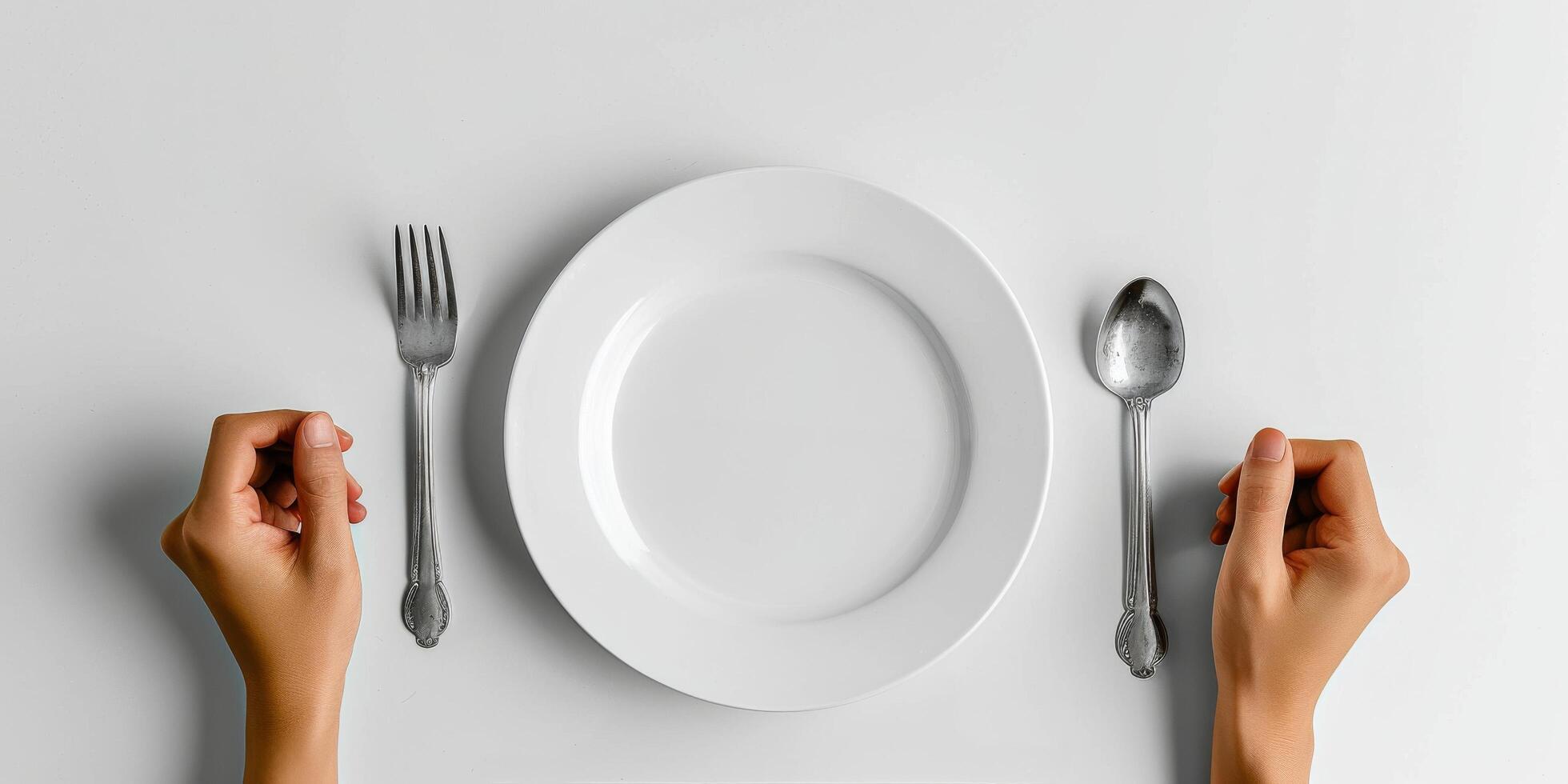 Hands poised to eat at a dining table set with a plate, fork, and spoon ready for a meal photo