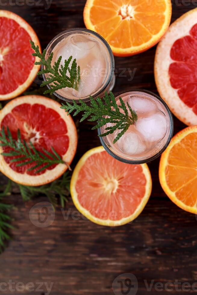 Alcoholic cocktail with grapefruit and citrus, ice and juice, drink glass on a wooden board, old rustic style. photo