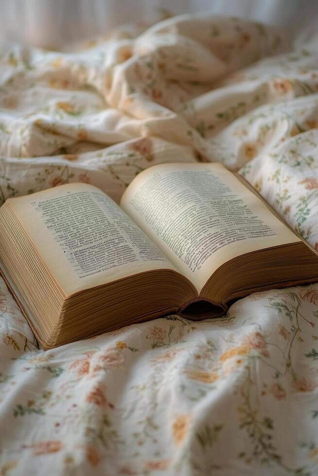 A vintage open book resting on a floral patterned bedspread in soft morning light photo