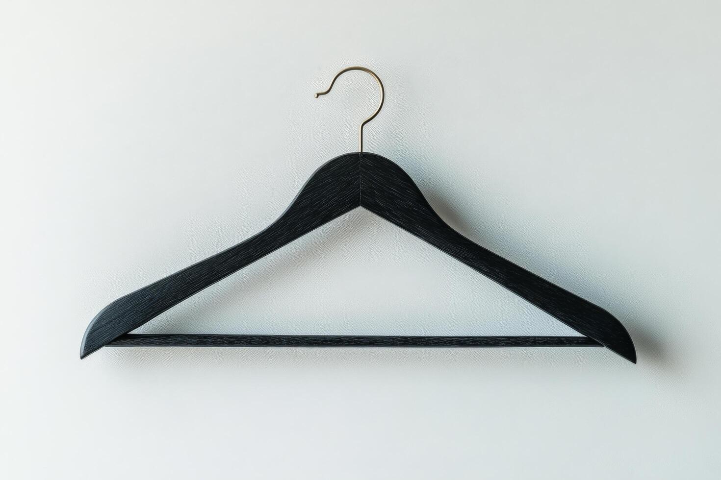 A simple black wooden hanger against a textured gray wall in a minimalist setting photo