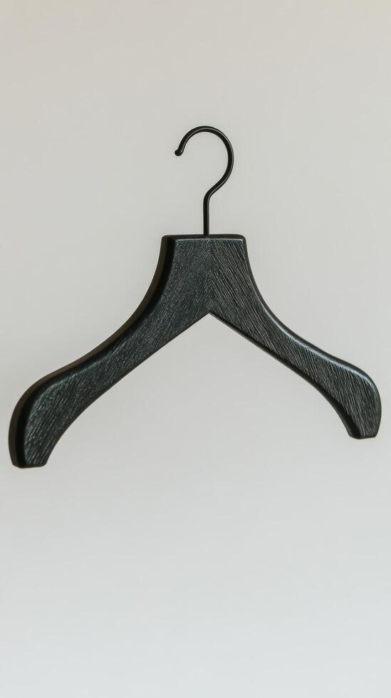 Black wooden hanger with metal hook against a plain background for organizing clothing items photo