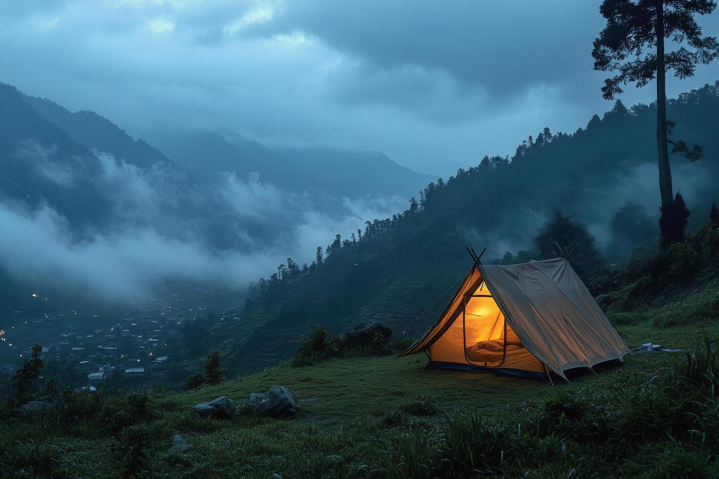 A solitary tent glows warmly in a misty mountain landscape during twilight hours photo