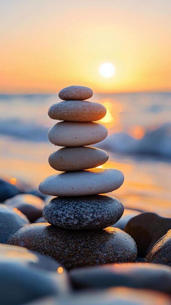Balanced stones stacked on a beach during sunset with waves gently lapping at the shore photo