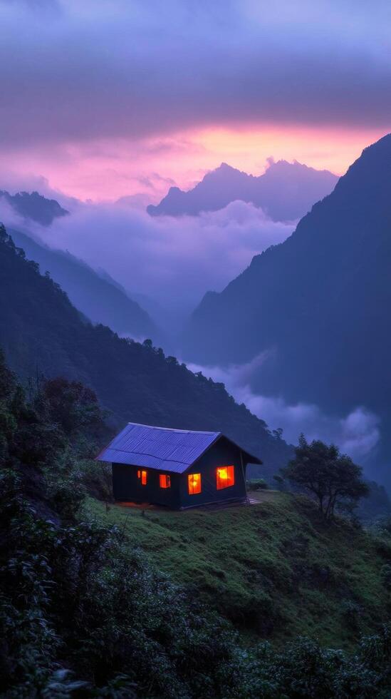 A cozy tent glows warmly in the mountains at dusk surrounded by misty peaks photo