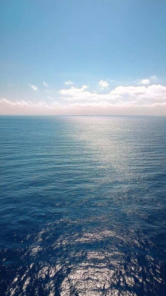 Calm ocean waters reflect the sky on a sunny day with scattered clouds photo