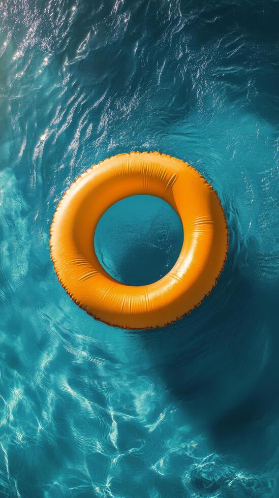 A bright yellow float ring floats on clear blue water during a sunny day at the pool photo