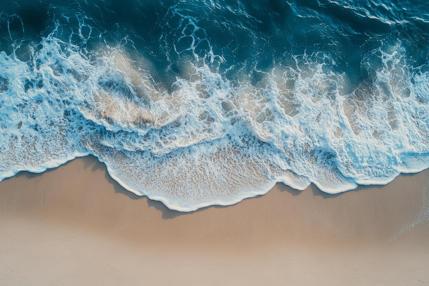 Gentle ocean waves lapping against a sandy beach captured from above during daylight hours photo
