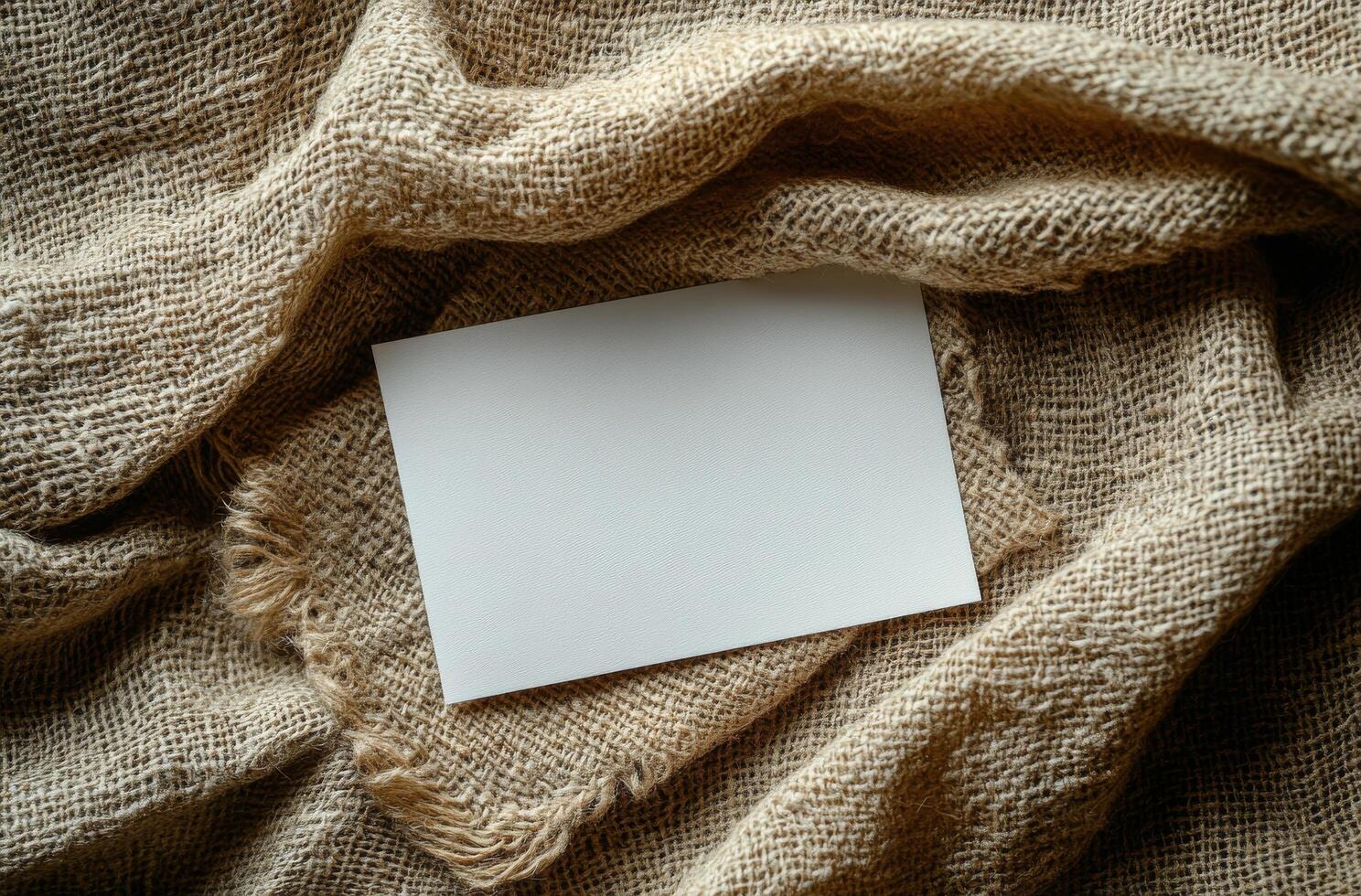 Blank card resting on textured burlap fabric creates a simple and rustic background composition photo