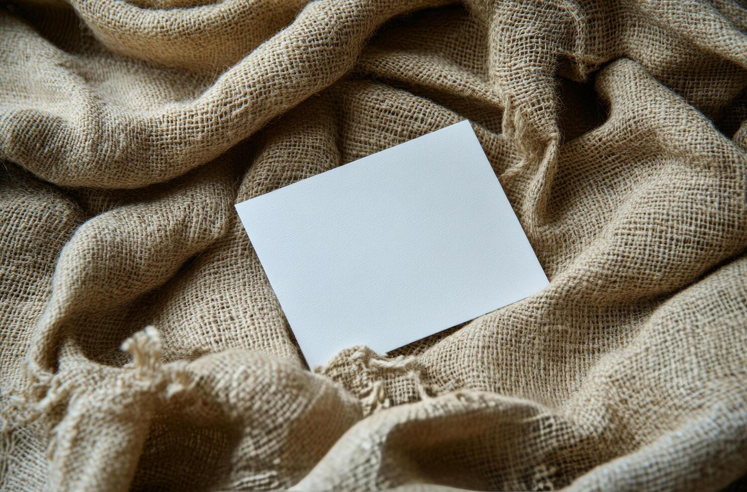 Blank card resting on textured burlap fabric creates a simple and rustic background composition photo