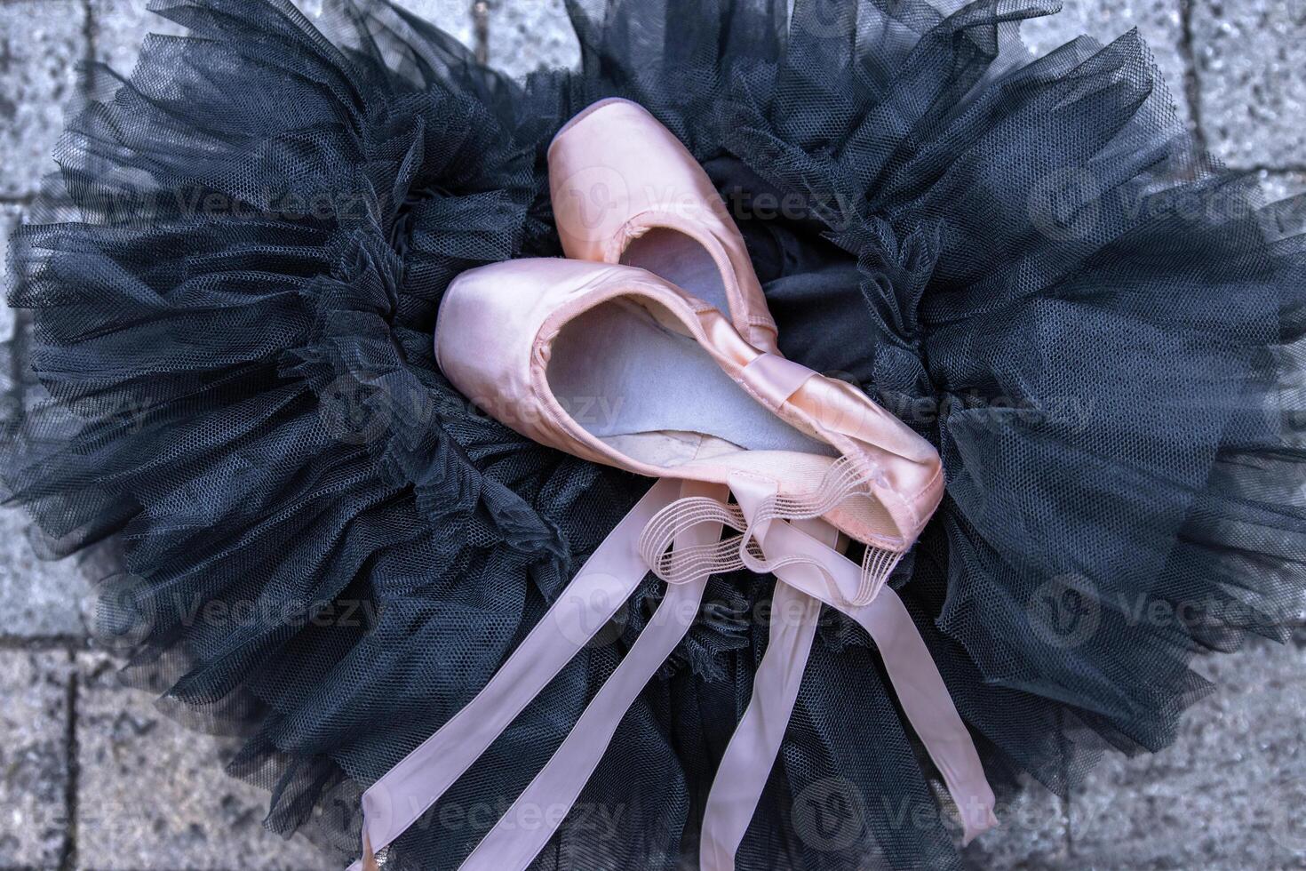Closeup of the pink ballet pointe shoes laying on the black chif photo