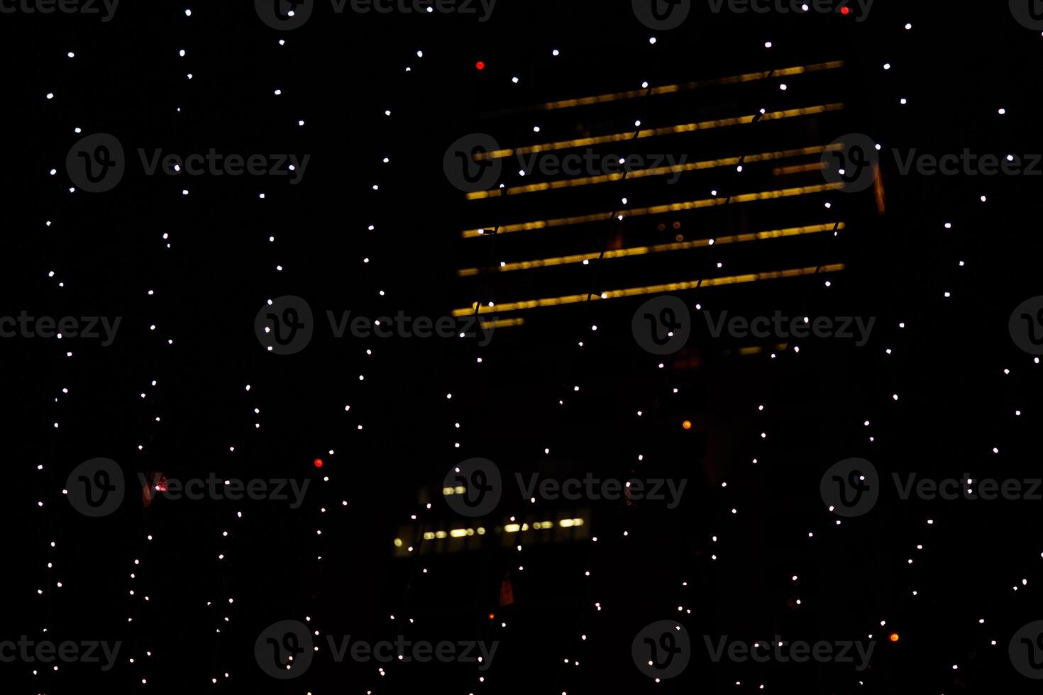 Abstract view of light strings hanging against a city building in the nighttime. Twinkling lights in the night, highlighting a dimly lit building in the background. Germany, Berlin photo