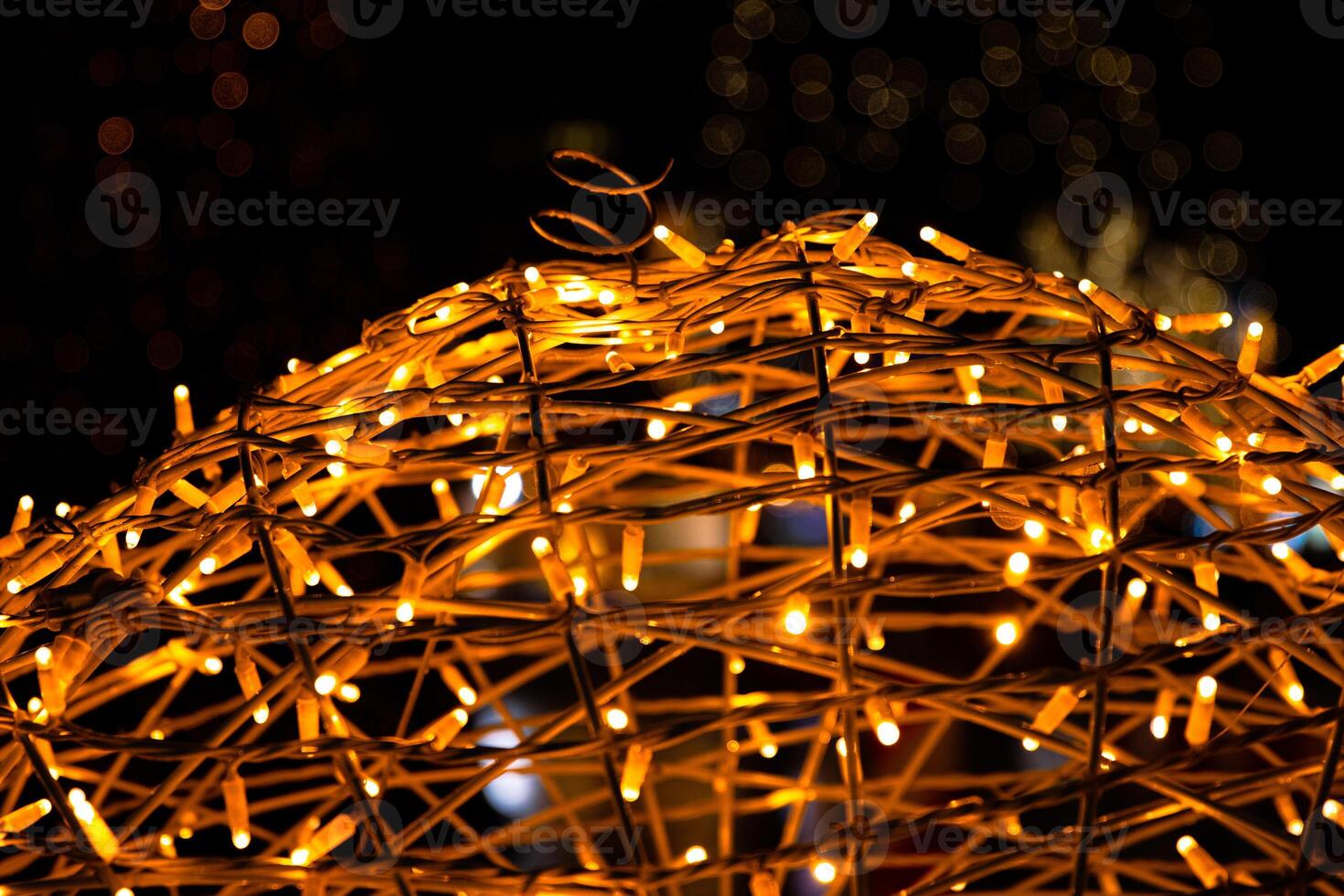 Closeup of intertwined golden string lights. Abstract view of crisscrossing glowing yellow LED garland with small bright bulbs, radiating light against a dark background. Berlin, Germany. Copy space photo