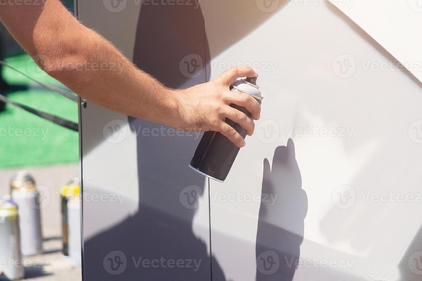 Man doing graffiti, holding spray can with hand. Spray aerosol paint for graffiti photo
