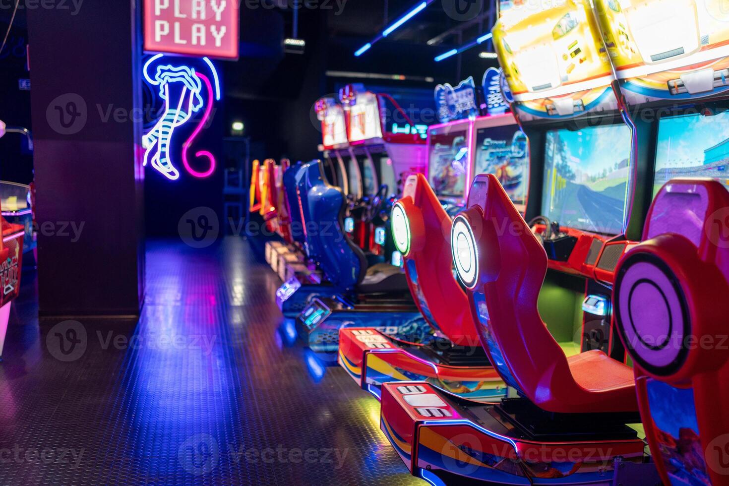 Empty gaming chairs in illuminated arcade game zone in shopping center photo