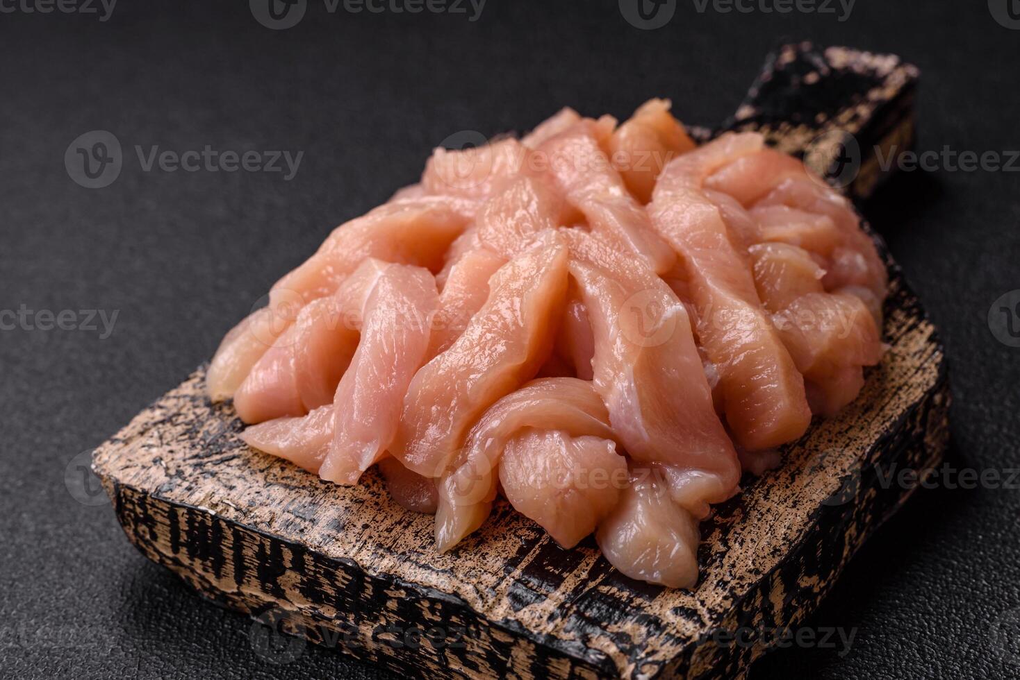 Raw chicken fillet cut into strips with spices and herbs photo