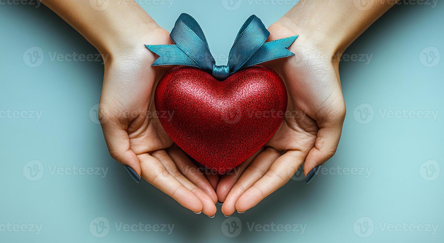 Hands holding a glittery red heart gift. Two hands gently cradle a bright red heart adorned with a blue ribbon, symbolizing love and care in a serene setting. photo