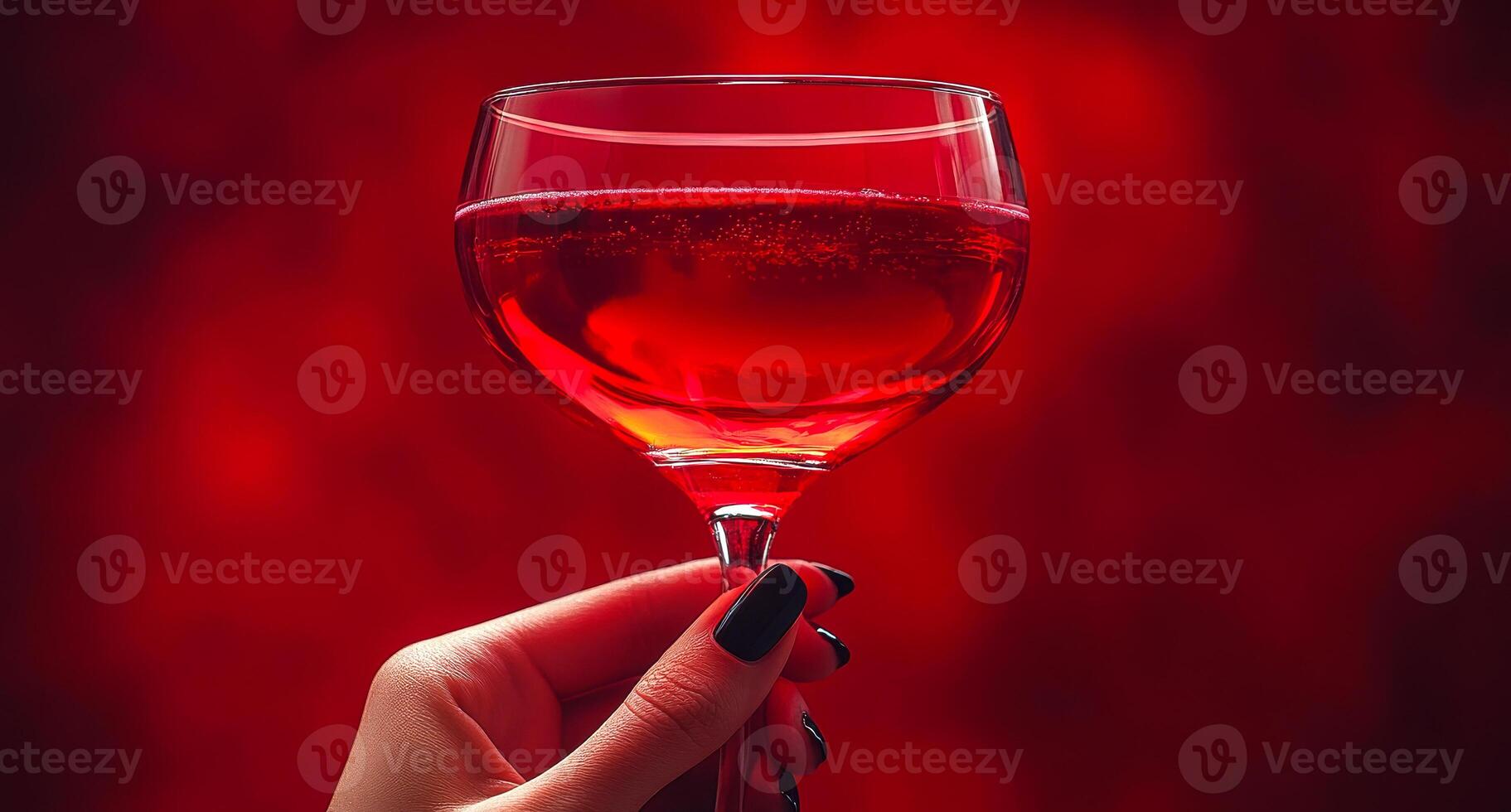 A person is holding a glass of red wine. The wine is in a wine glass and the person is holding it up to their face. The image has a mood of celebration and enjoyment photo