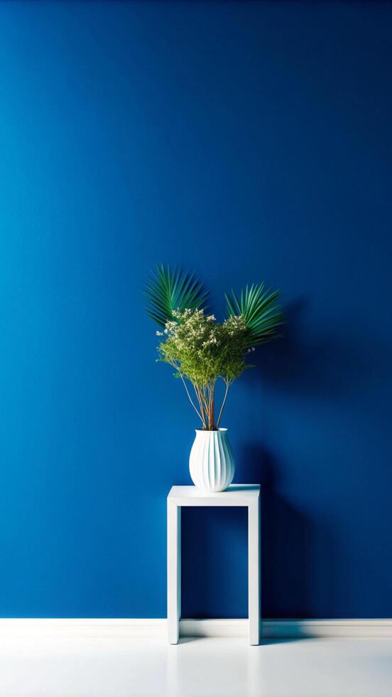A white vase with a plant on a table in front of a blue wall photo