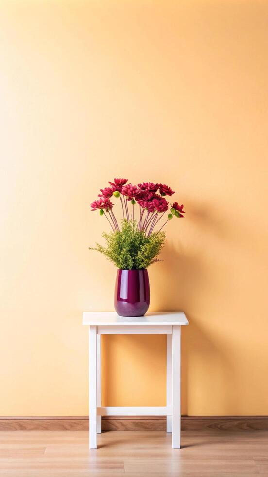 A vase of flowers sits on a table in front of an orange wall photo