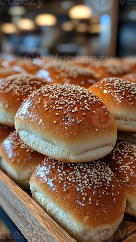 Freshly baked buns covered with sesame seeds resting on shelf photo