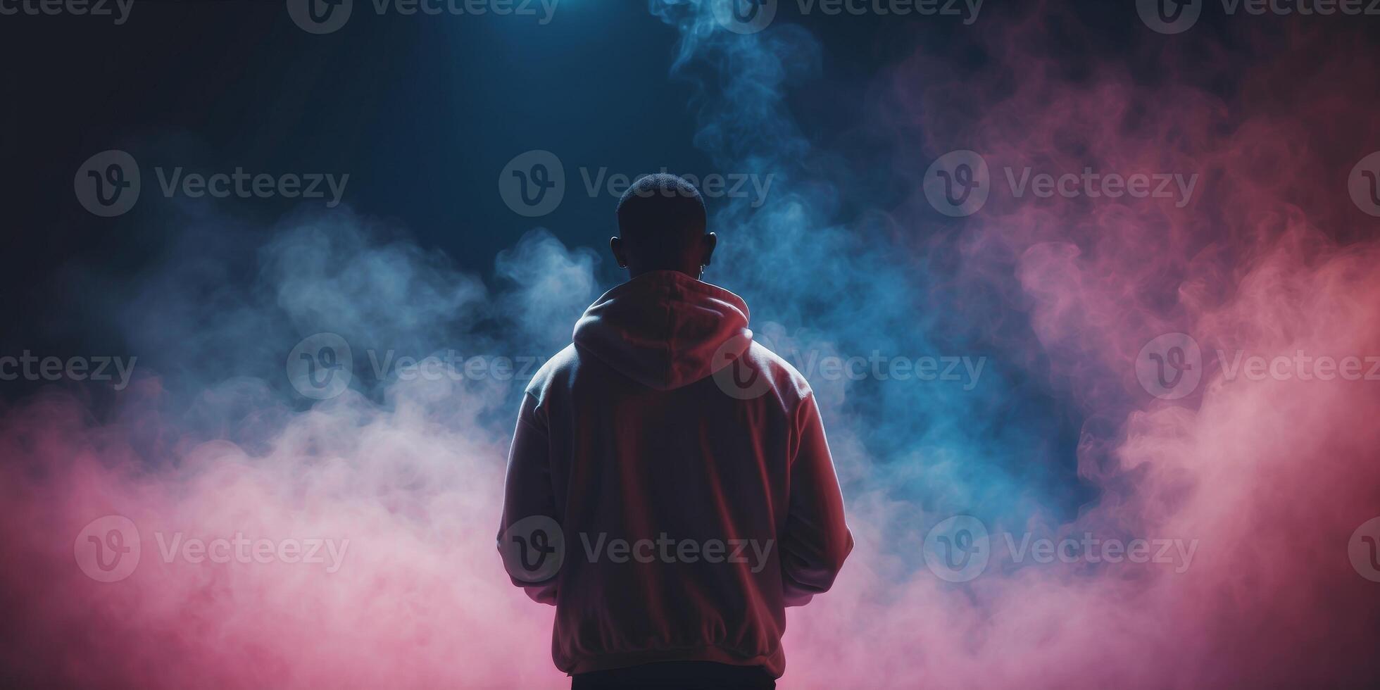 A man in a hoodie standing in front of a smoke cloud photo