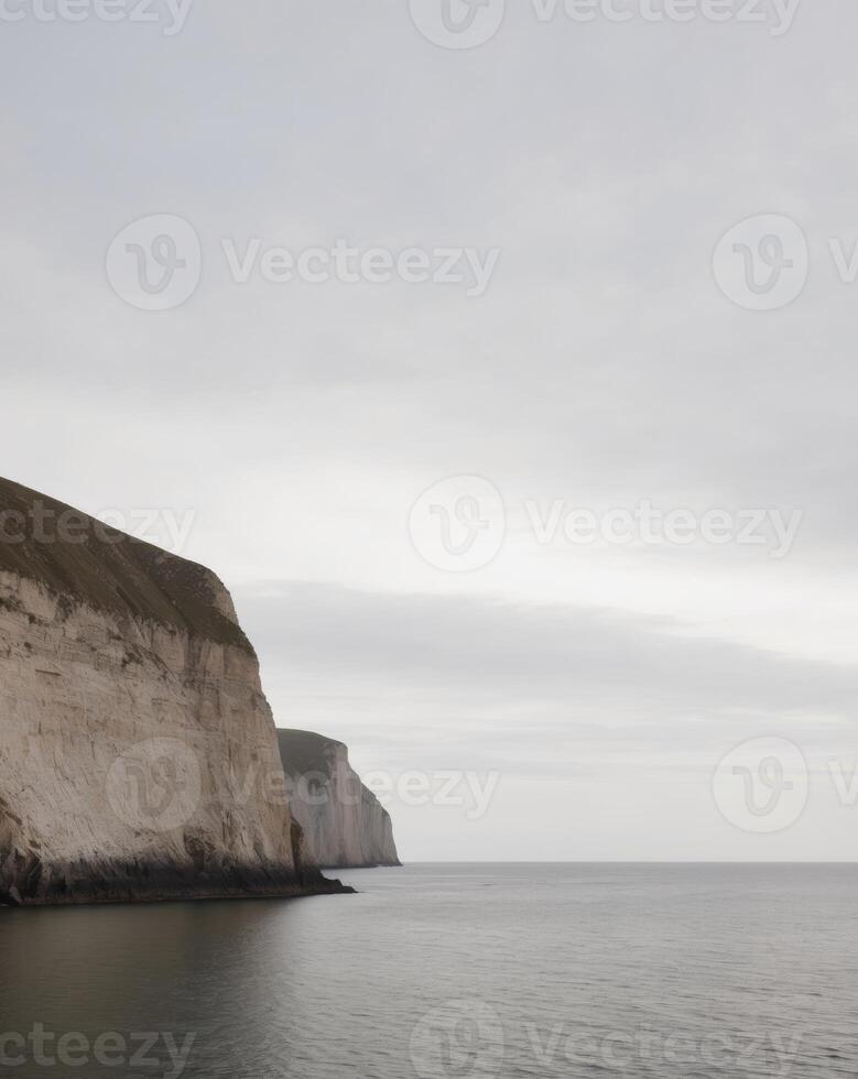 A white cliff on the ocean with a boat in the distance photo