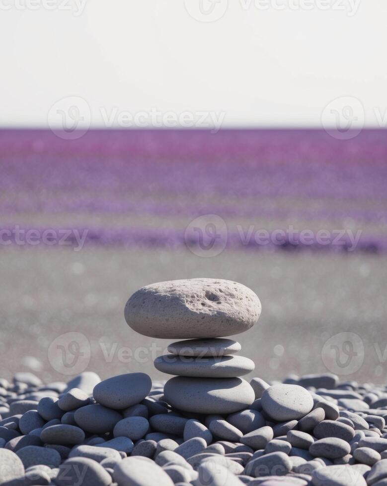 A stack of rocks on a beach with purple flowers photo