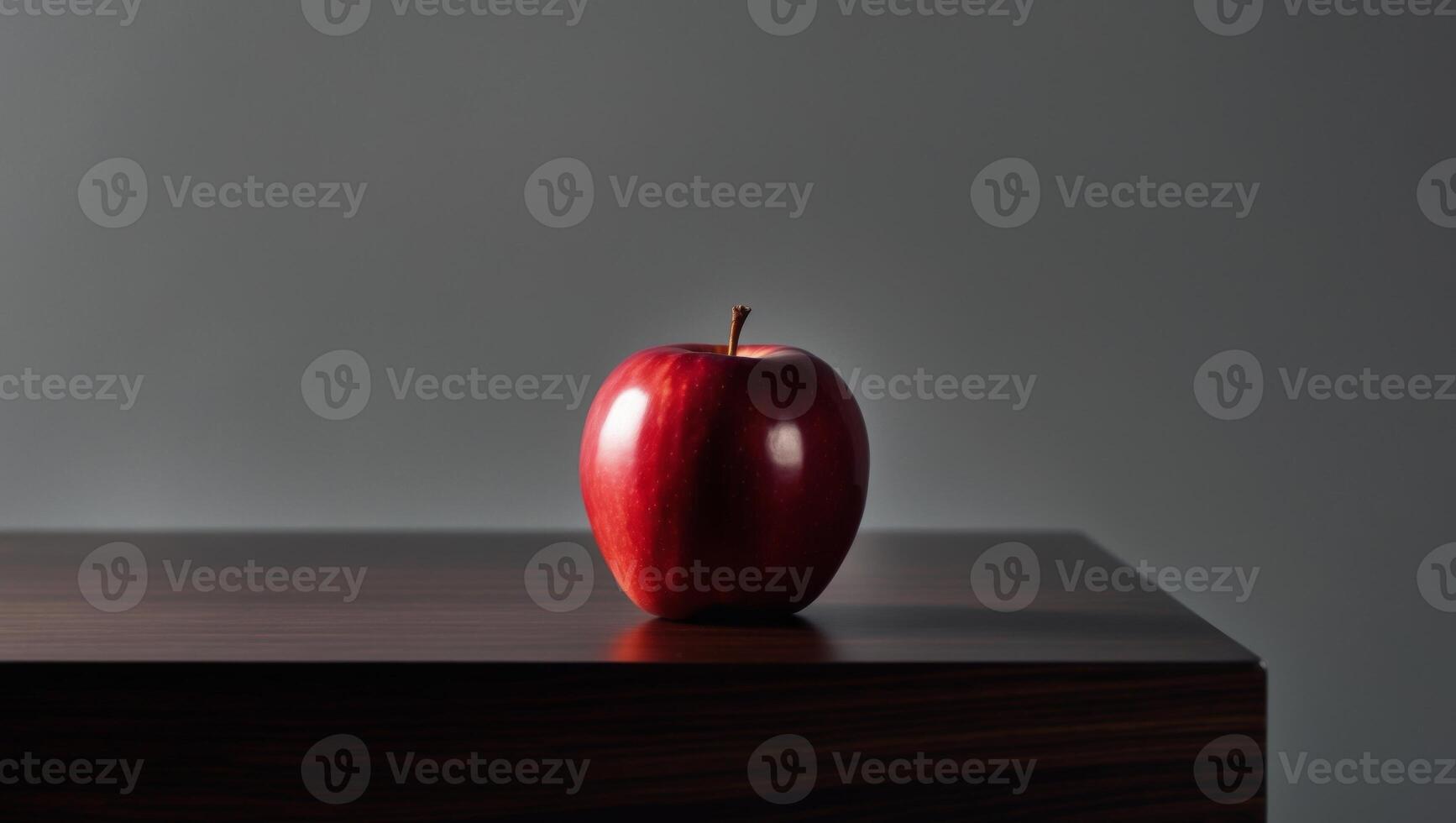 A single red apple sitting on top of a table photo